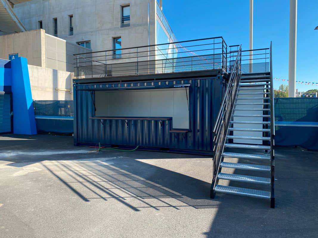 Container bar rooftop bleu avec escalier et terrasse sur le toit