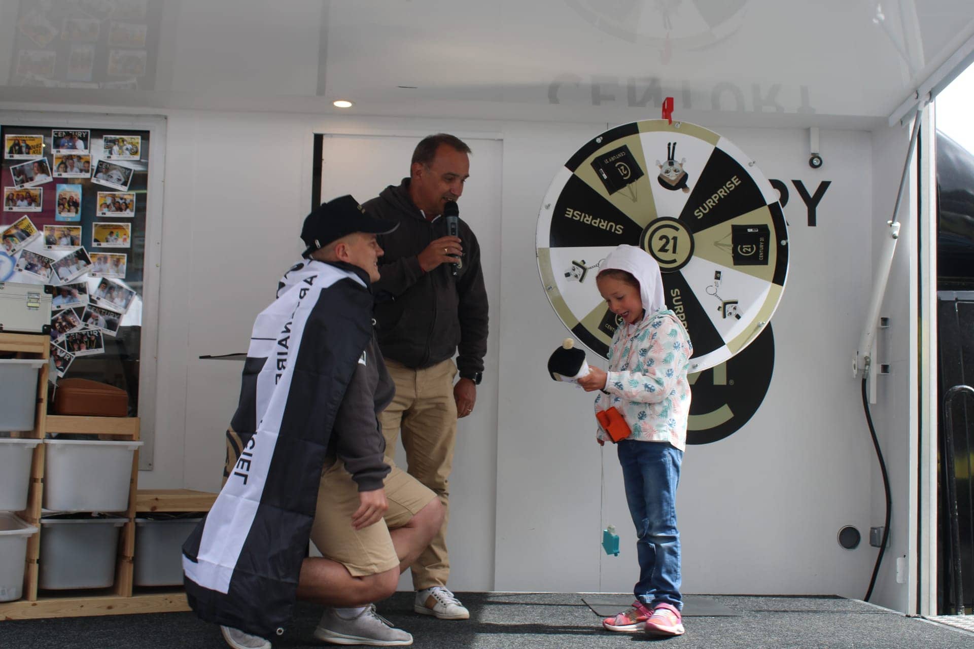 Camion podium Century 21 - animateur au micro et enfant faisant tourner la roue de la fortune à bord