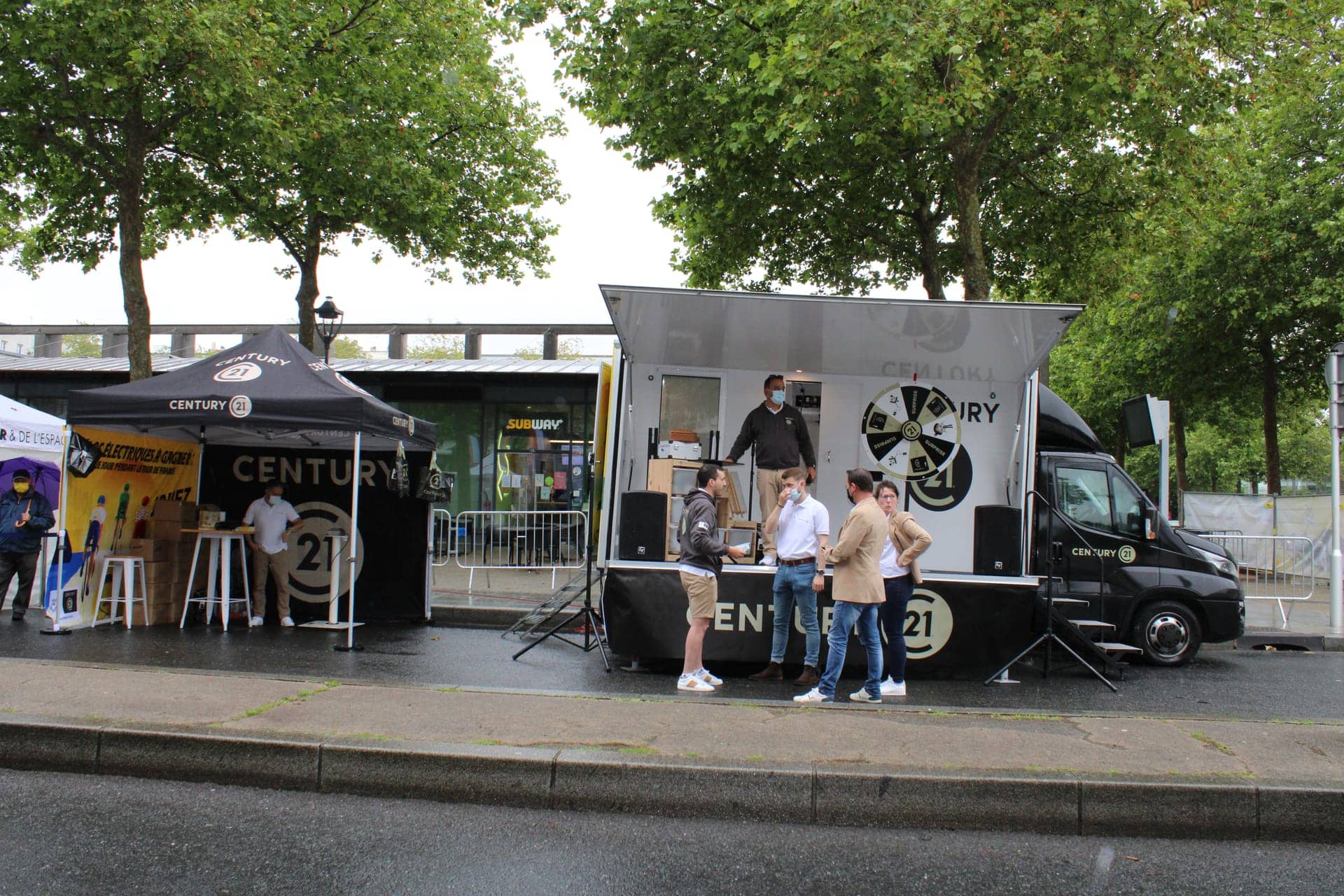 Camion podium Century 21 - dispositif complet avec barnums et scène installé sur une place de centre-ville