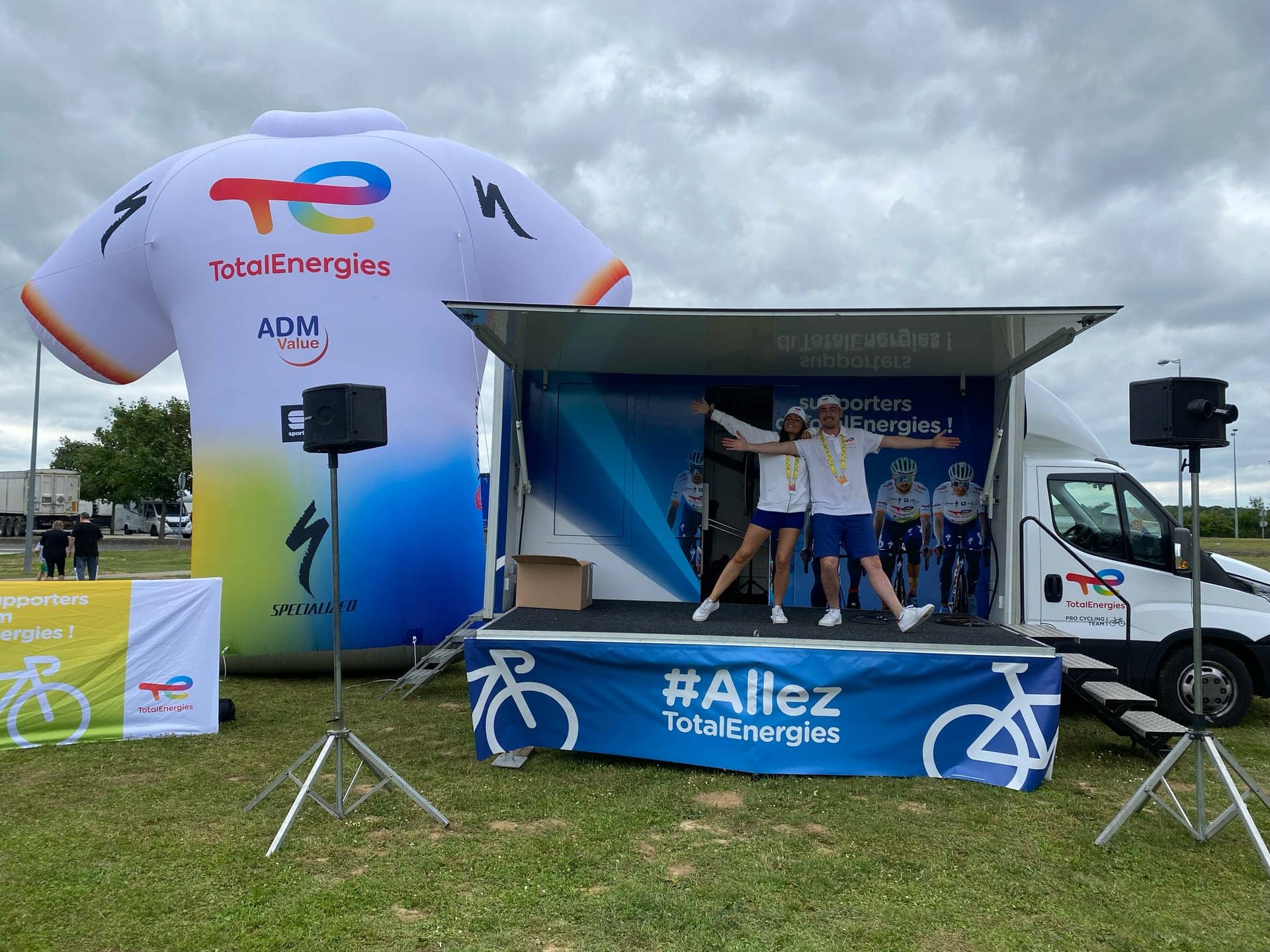 Camion podium TotalEnergies - scène déployée aux couleurs #Allez à côté d'un maillot cycliste gonflable géant