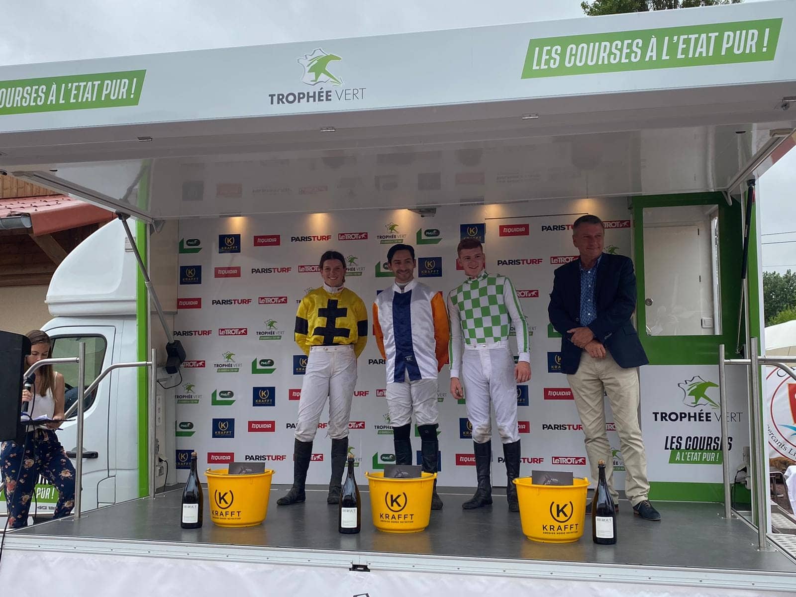 Camion podium Trophée Vert - remise des prix des jockeys sur la scène, magnums alignés au premier plan