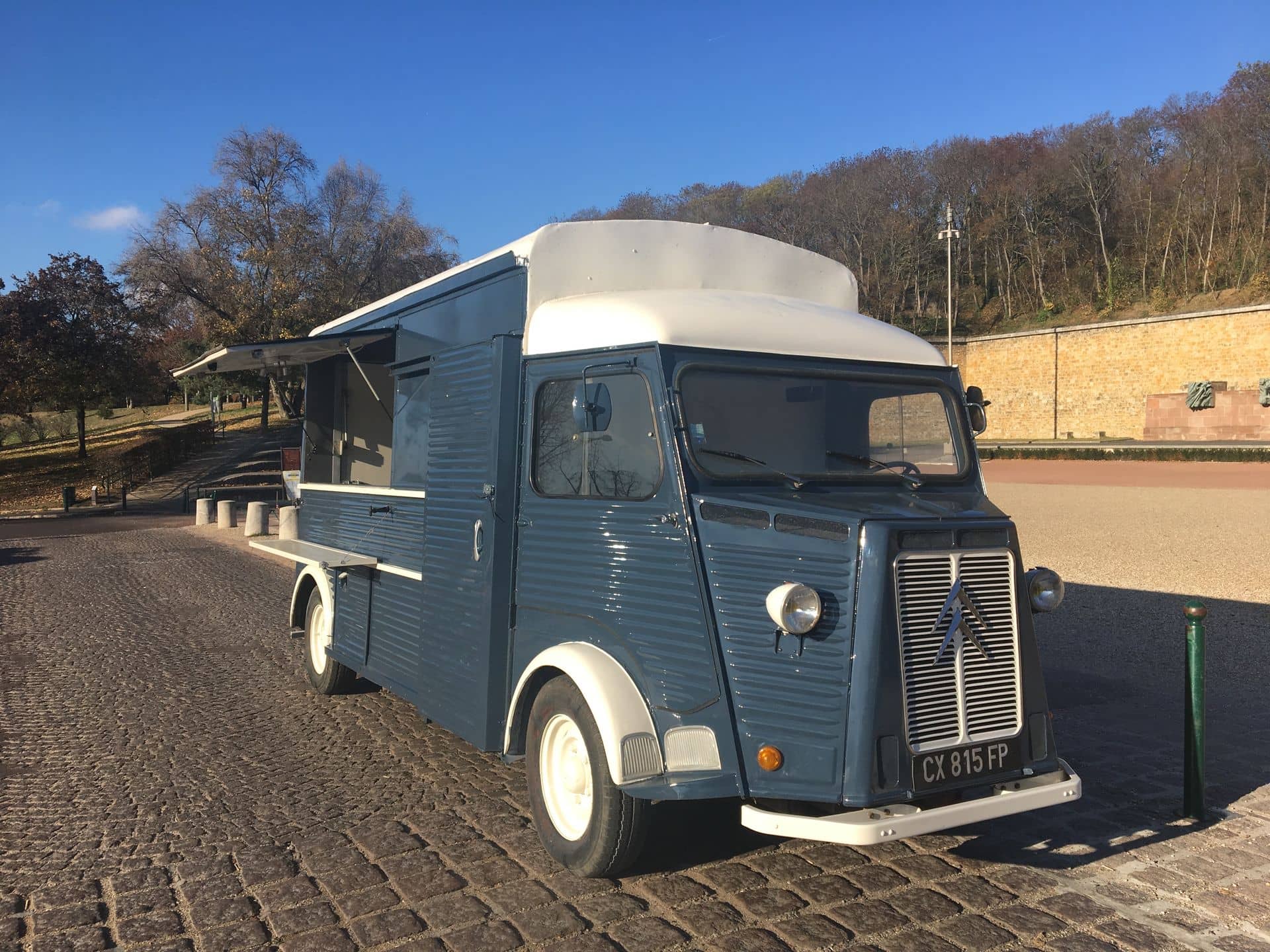 Citroën HY bleu-gris avec son comptoir latéral déployé sur une esplanade pavée