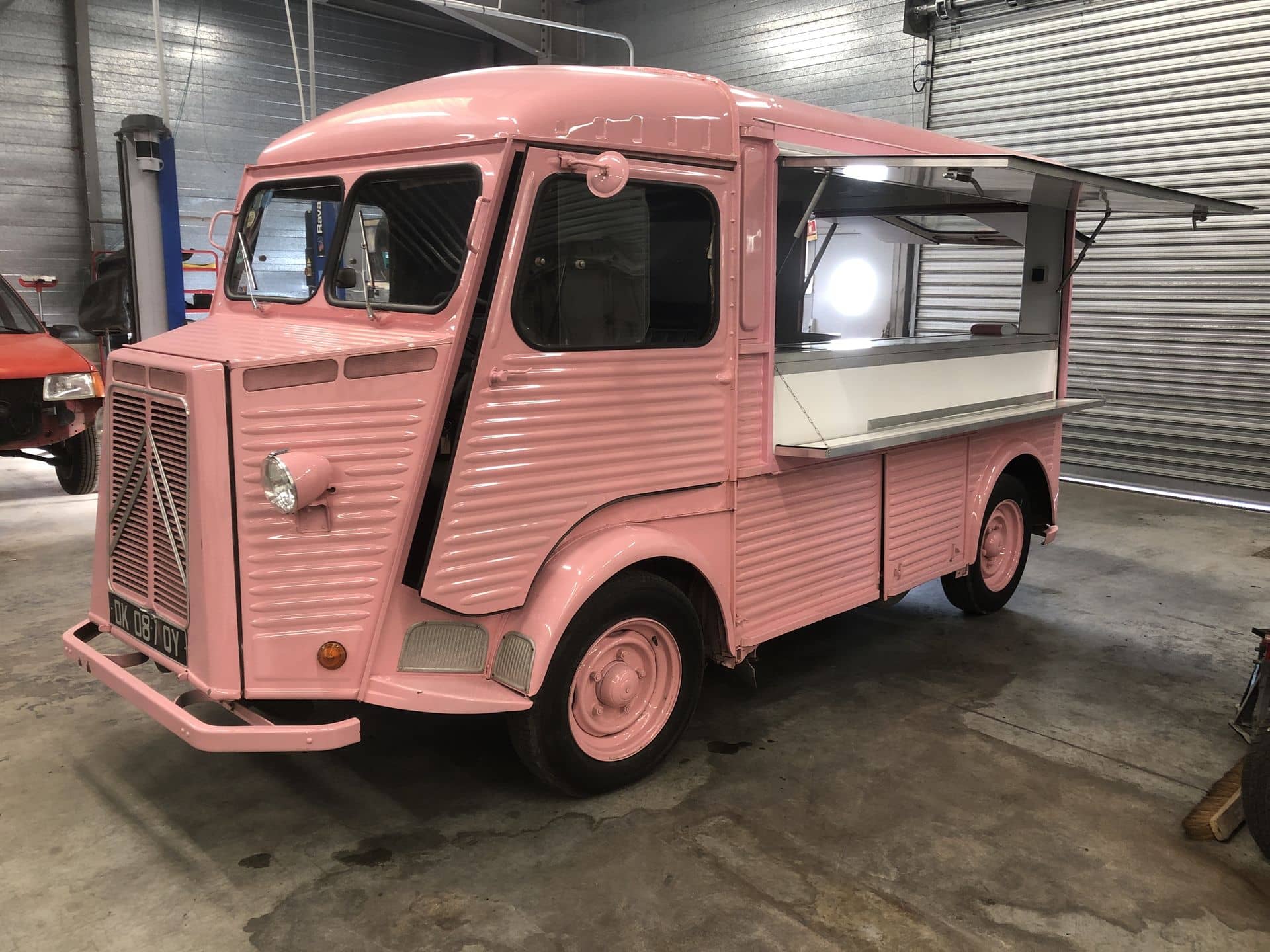 Citroën HY rose avec comptoir et auvent latéral ouverts sous éclairage d'atelier