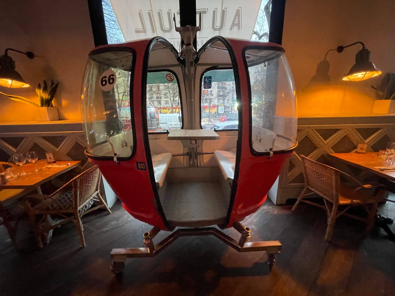 Télécabine Megg numéro 66 vue de face dans la salle de la brasserie Auteuil, portes ouvertes sur une table