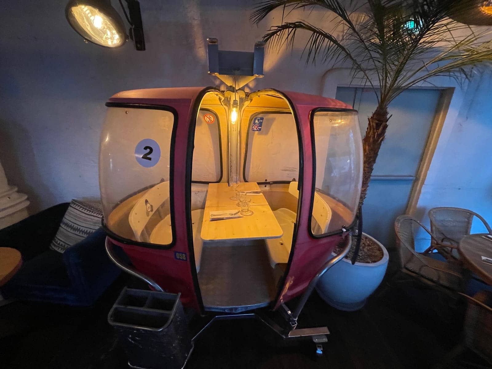 Télécabine Megg numéro 2 installée près d'un palmier dans la salle de la brasserie Auteuil