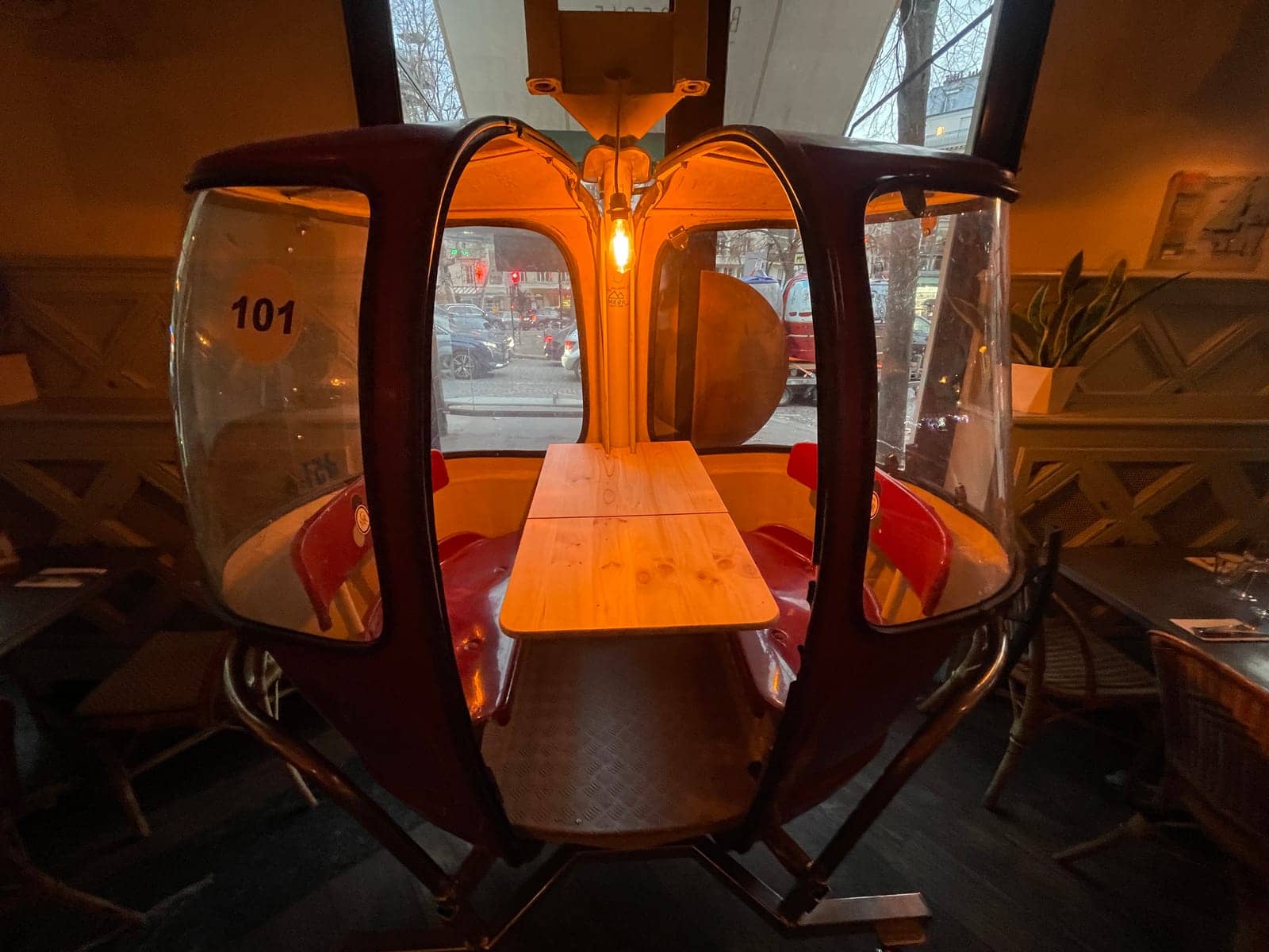 Intérieur d'une télécabine Megg aménagée en table de restaurant, ampoule suspendue et couverts dressés