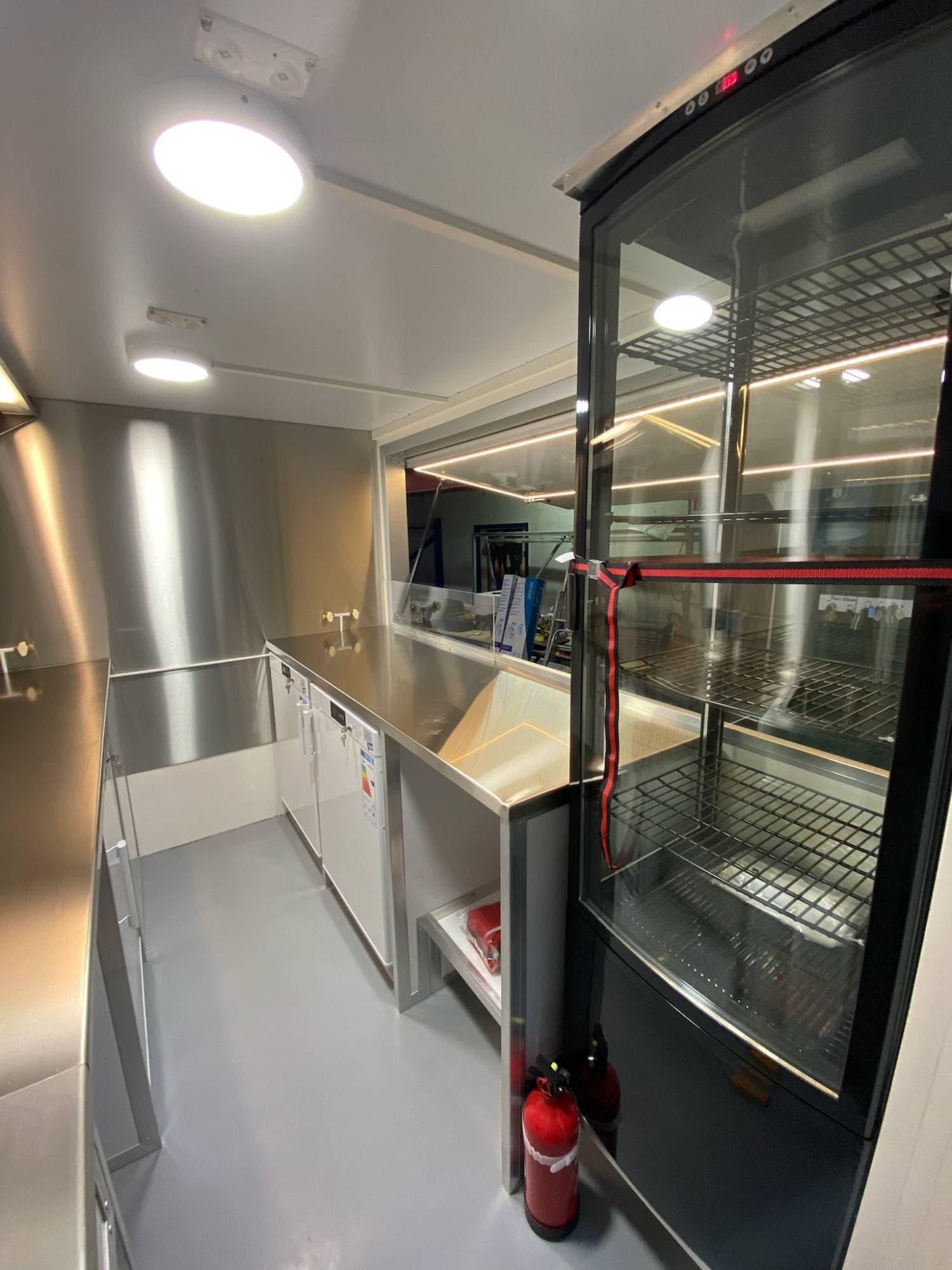 Arrière camion crêpes avec vitrine d'exposition éclairée, plans de travail inox et extincteur de sécurité