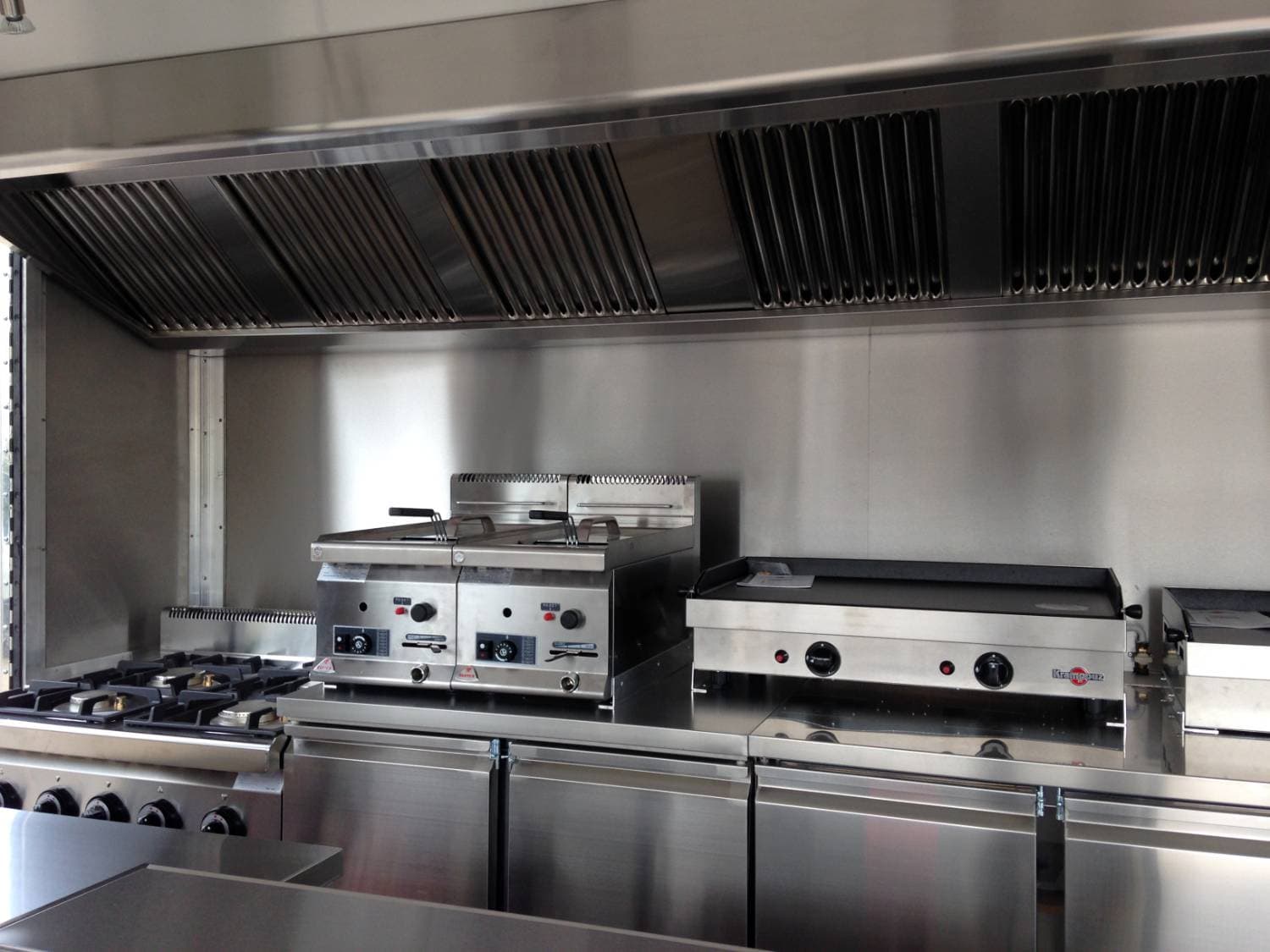 Cuisine professionnelle inox du food truck burger avec friteuses, plancha et hotte aspirante en acier
