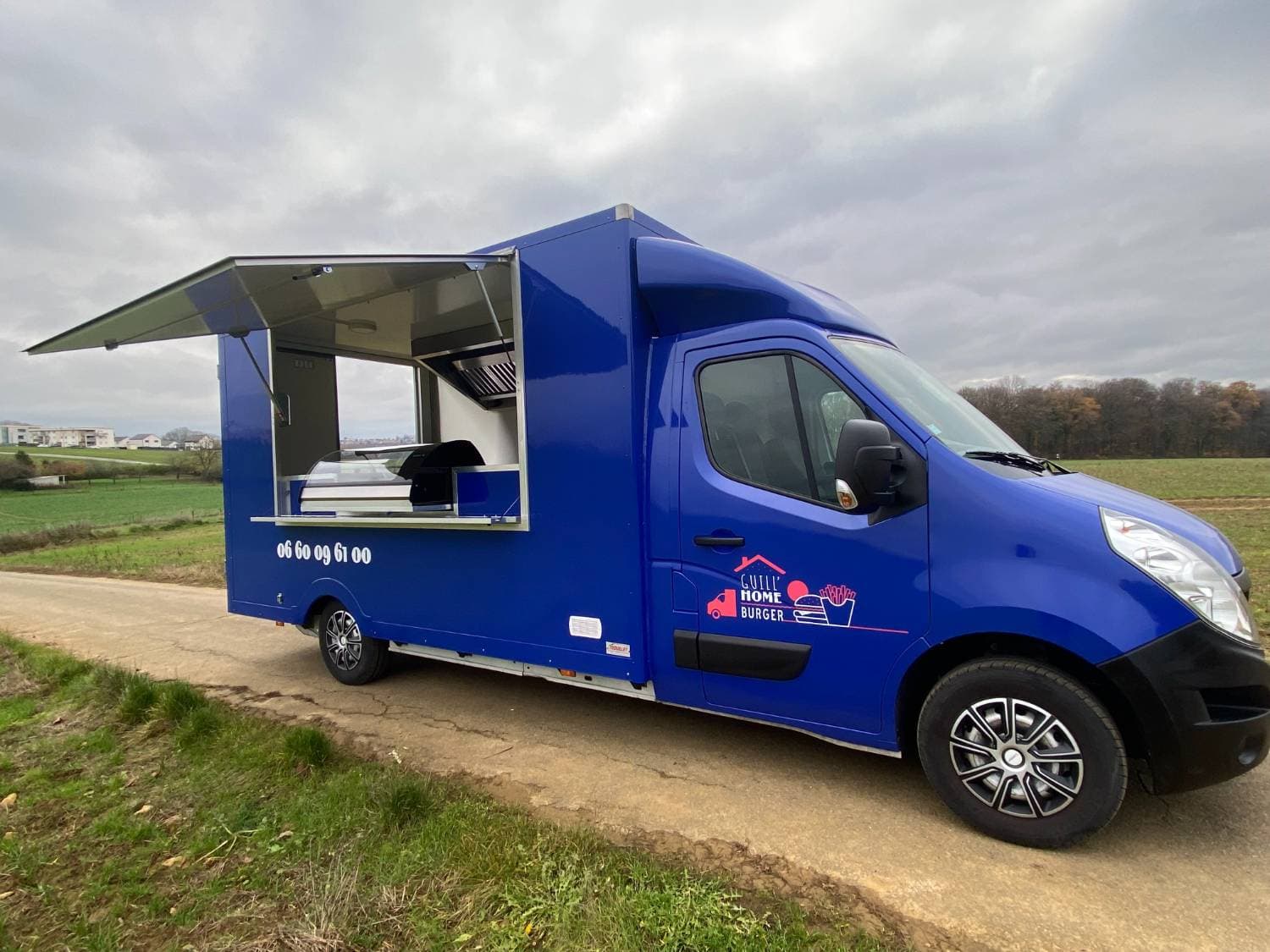 Food truck Guill'Home Burger bleu ouvert côté service avec hotte, plancha et comptoir professionnel visible