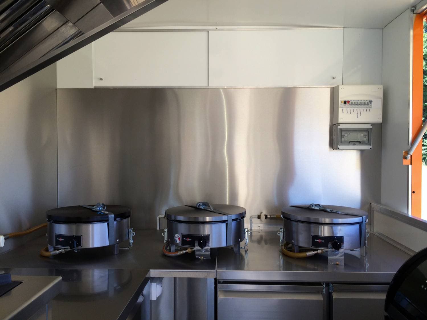 Intérieur cuisine du food truck La Crépitante avec trois crêpières professionnelles en inox et hotte aspirante