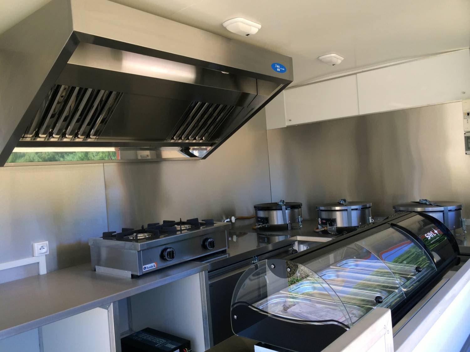 Aménagement intérieur du camion crêpes avec plaques de cuisson, crêpières, vitrine réfrigérée et hotte professionnelle