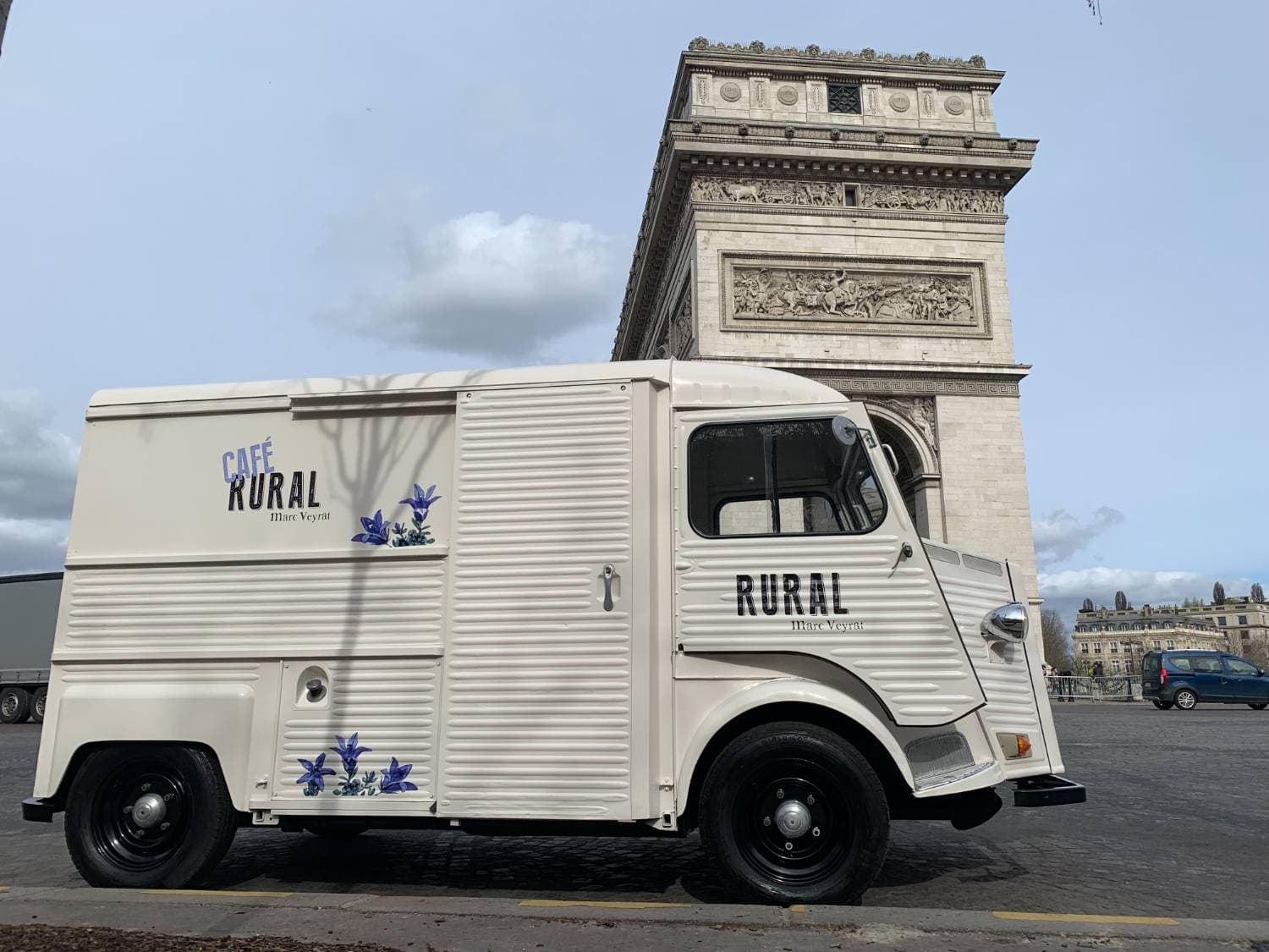 Citroën HY blanc Café Rural Marc Veyrat stationné devant l'Arc de Triomphe à Paris — vue latérale avec covering floral bleu