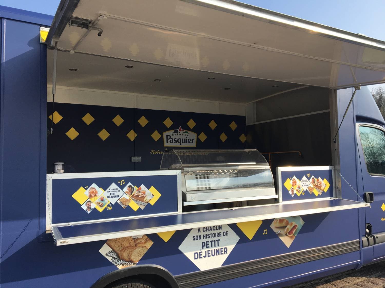 Food truck Brioche Pasquier volet ouvert avec comptoir vitrine et décor bleu marine et losanges dorés
