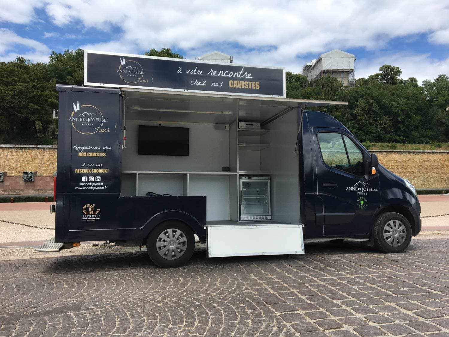 Wine truck Anne de Joyeuse bleu nuit volet ouvert avec bar à vins écran et réfrigérateur sur esplanade