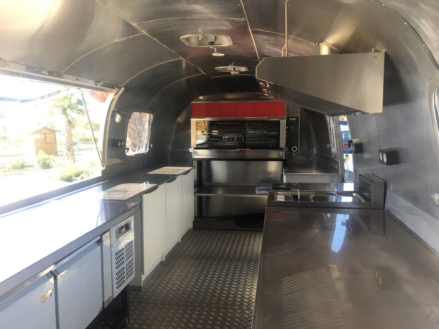 Intérieur Airstream - cuisine inox complète avec rôtissoire, plans de travail et sol damier aluminium