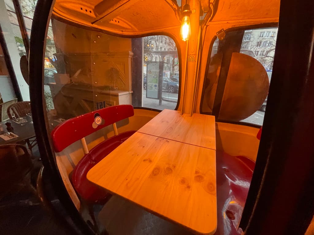 Intérieur de la télécabine - table en bois massif, banquettes rouges et éclairage Edison