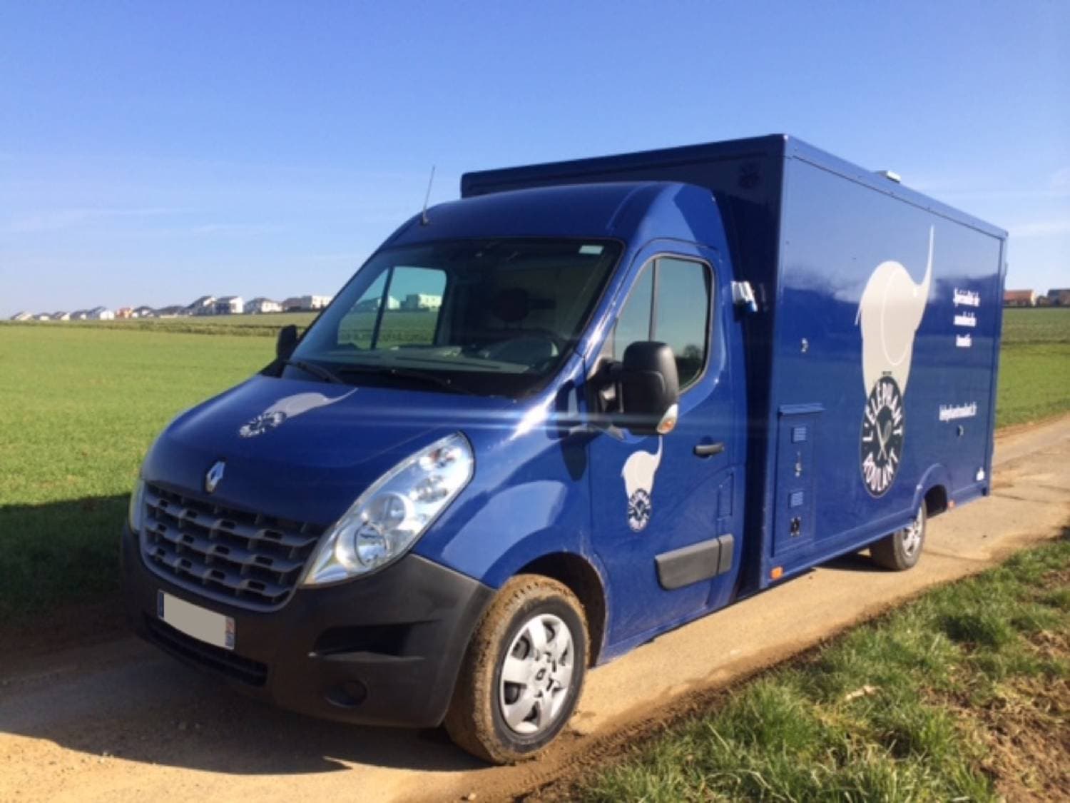 Food truck Renault Master bleu foncé L'Éléphant Roulant stationné en campagne avec covering personnalisé