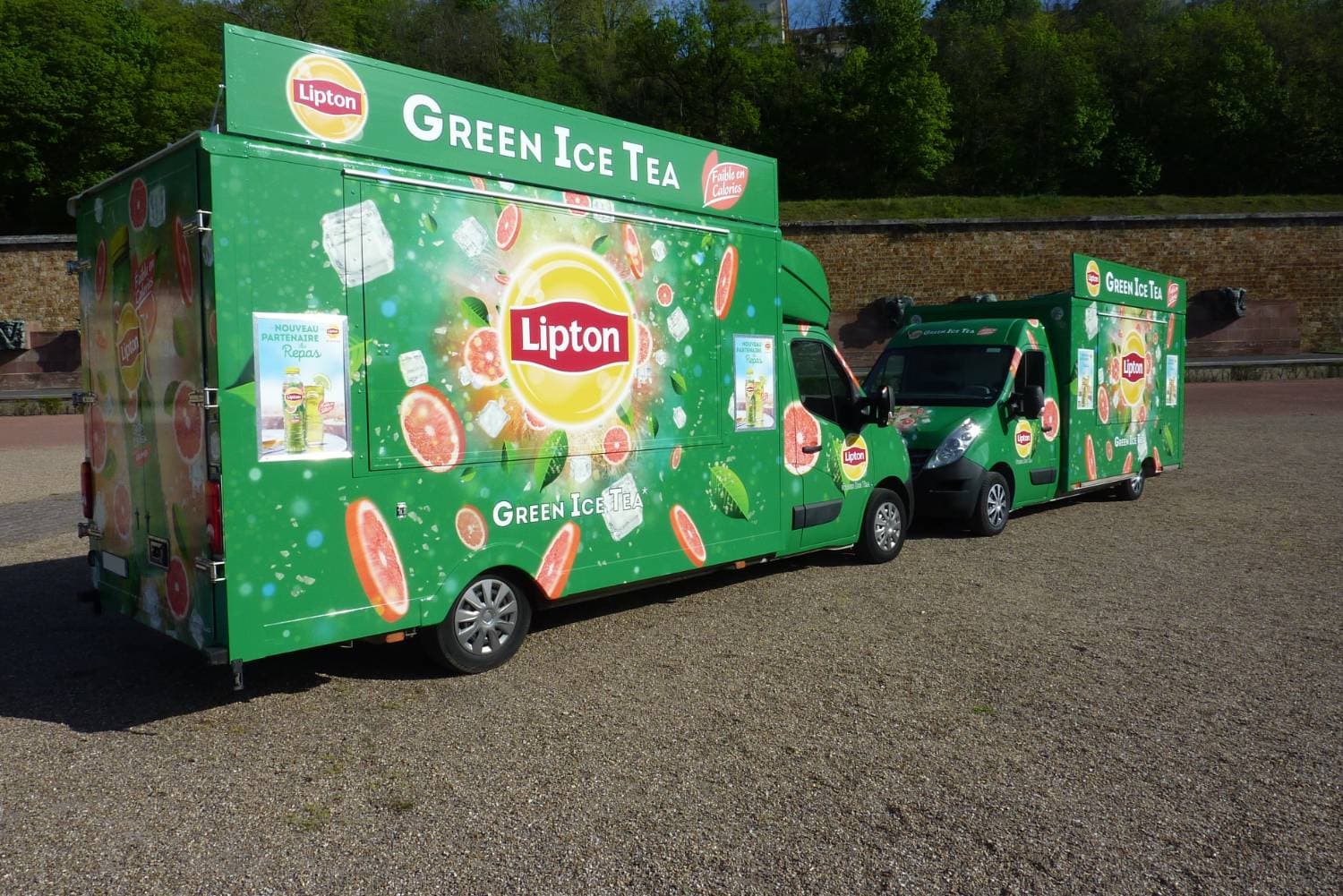 Deux Renault Master Lipton Green Ice Tea verts avec covering fruits et glaçons sur une esplanade
