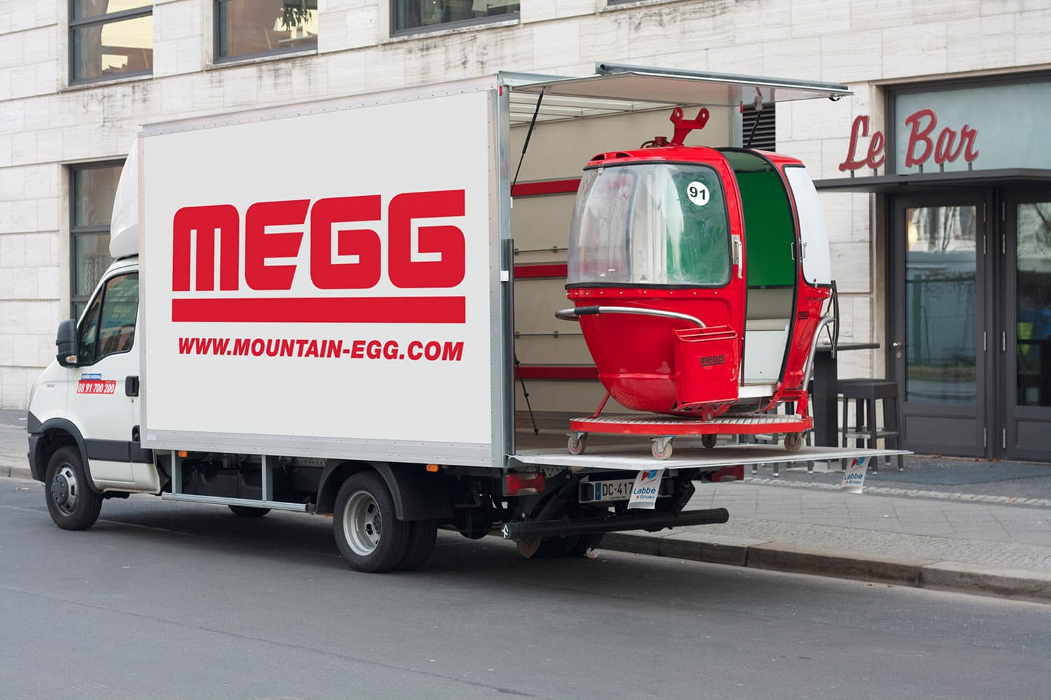 Livraison d'une télécabine MEGG rouge par camion - transport clé en main